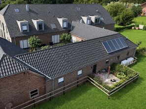 A residential building with multiple skylights and solar panels on the roof, surrounded by a well-maintained lawn and garden. - Lindenglück Vacation Rental (Uedem)