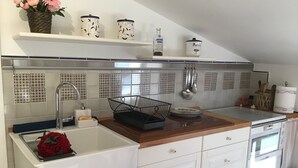 Una cocina con gabinetes blancos, un fregadero, un escurreplatos y una estufa.
