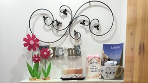 Un gabinete blanco con un letrero metálico decorativo, un cartel de bienvenida, un póster de viaje y dos bolsas colgadas de las puertas del mueble.