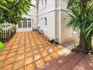 A paved courtyard with a tiled floor, a wooden fence, and potted plants. - A modern well-appointed apartment in a convenient location. (Torquay)
