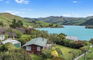 A house with a green roof, surrounded by lush greenery and a lake.
