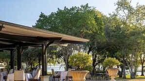 Un espace extérieur aménagé en terrasse, avec des tables et des chaises, une pergola et de grands jardinières.