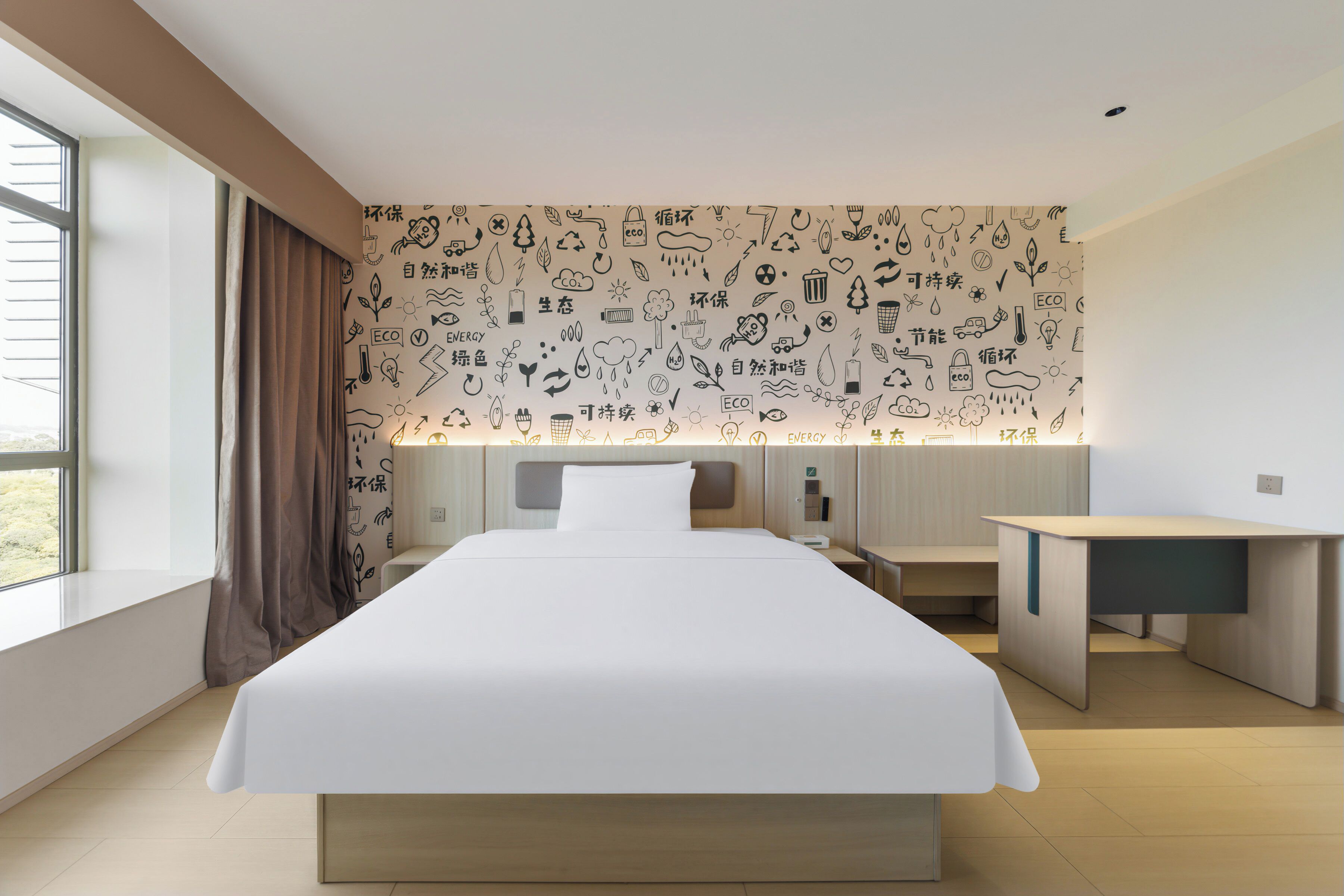 Habitación de hotel moderna con una cama grande, un escritorio y una pared decorada con iconos de temática ecológica.