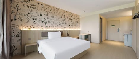 Habitación de hotel con una cama grande, mesitas de noche, un escritorio y un baño visible a través de una puerta abierta.