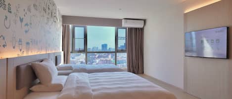 Quarto de hotel com uma cama grande, televisão, janela com cortinas e parede com ícones.