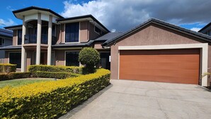 A modern two-story house with a garage, a well-maintained lawn, and a clear sky.