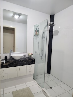 A modern bathroom with a glass-enclosed shower, a white sink, and a marble countertop.
