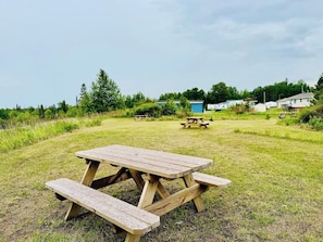 A picnic table in a grassy field with a clear sky. - 1818 Trailside Birch - Cabin 1 (Grand Marais)