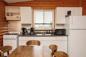 Eine Küchenzeile im Blockhausstil mit Holzvertäfelung, einem Herd, einer Spüle und einem Kühlschrank.
