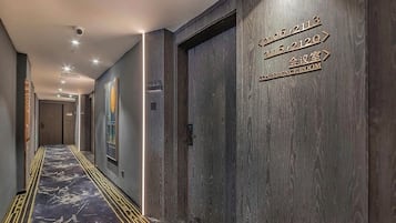 Pasillo de hotel con indicaciones hacia salas de conferencias y alfombra estampada.