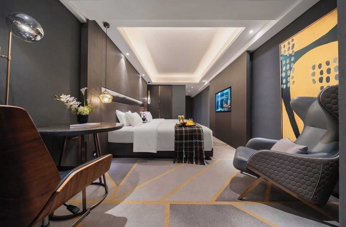 Una habitación de hotel moderna con una cama, un escritorio, una silla y una pequeña mesa con un florero.