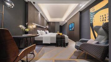 Una habitación de hotel moderna con una cama, un escritorio, una silla y una pequeña mesa con un florero.