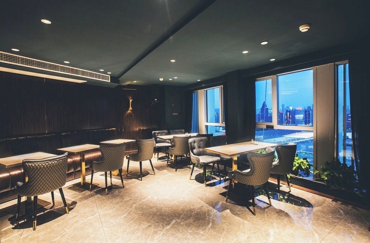 A modern dining area with a city view, featuring a mix of seating arrangements and a contemporary design.