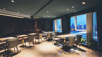 A modern dining area with a city view, featuring a mix of seating arrangements and a contemporary design.