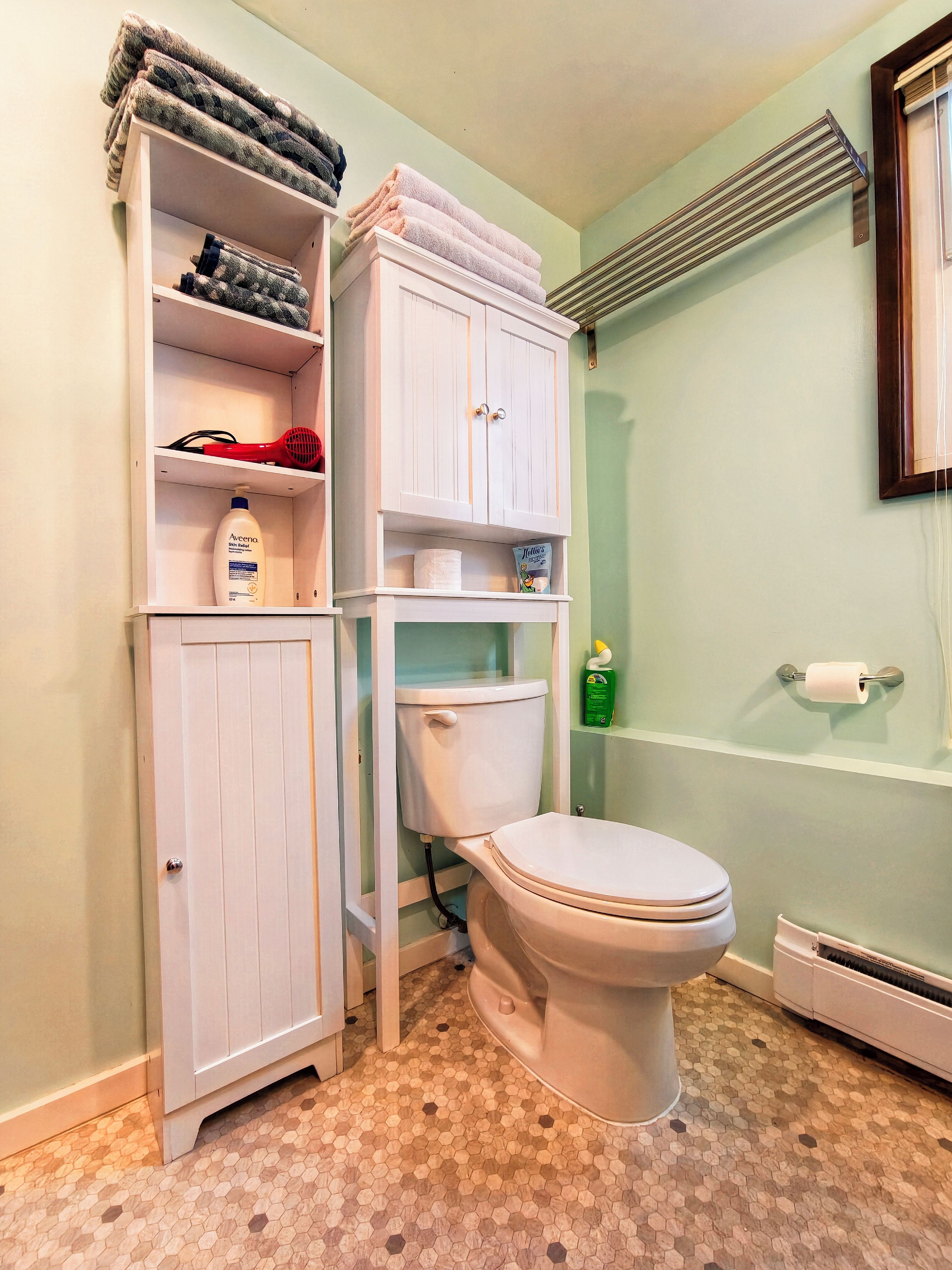 A bathroom with a toilet, a cabinet with towels, and a shower area.