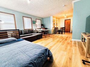 Een moderne woonkamer met een bank, een eettafel met stoelen en een televisie op een dressoir.