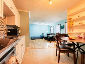A compact living space with a kitchenette, a dining area, and a bedroom.