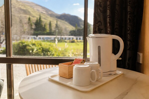 A coffee setup on a table with a view of mountains and greenery outside. - Ata Studios at Sundale Holiday Park (Wānaka)