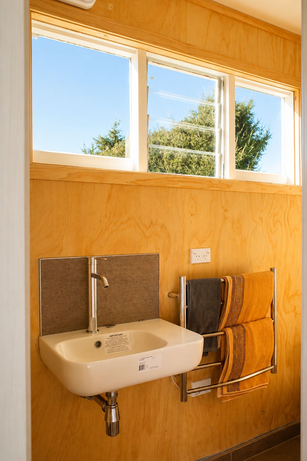A bathroom with a white sink, a towel rack with towels, and a window above the sink.
