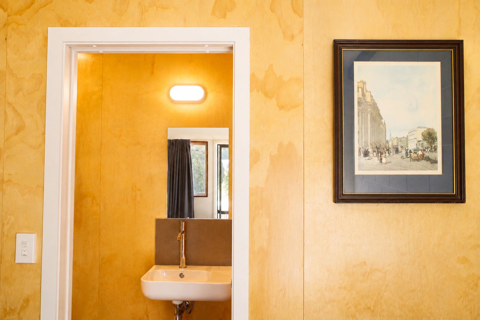 A bathroom with a sink, mirror, and a framed picture on the wall.