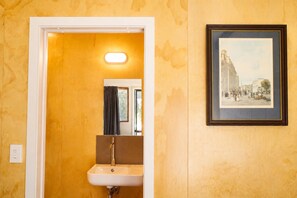 A bathroom with a sink, mirror, and a framed picture on the wall.