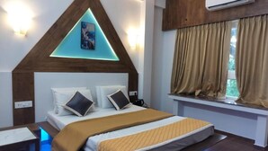Une chambre à coucher comprenant un lit, une table de chevet, une fenêtre avec des rideaux et un climatiseur fixé au mur.