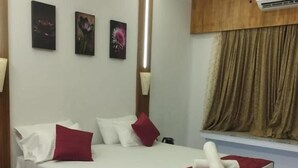 Une chambre à coucher moderne, avec un lit, une table de chevet, une fenêtre avec des rideaux et un climatiseur fixé au mur.