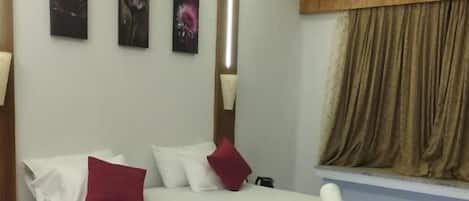 A modern bedroom with a bed, a bedside table, a window with curtains, and a wall-mounted air conditioner.