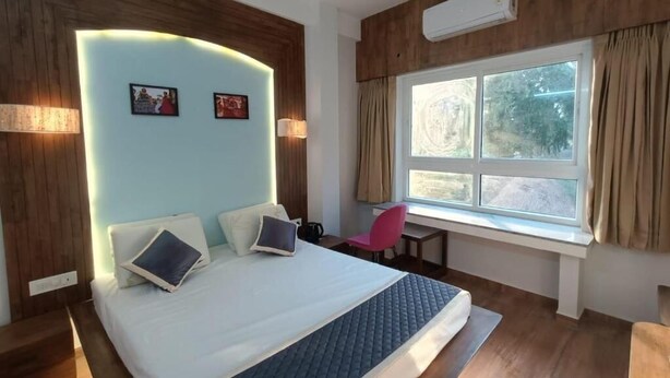 Une chambre à coucher avec un lit, un bureau, une chaise et une fenêtre avec des rideaux.