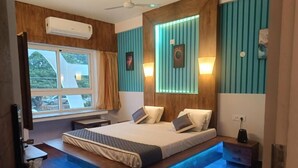 Une chambre à coucher comprenant un lit, des tables de chevet, une fenêtre et un climatiseur fixé au mur.