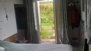 Ein Schlafzimmer mit einem Bett, einem Fenster und Blick auf einen Garten.
