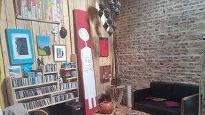 Ein gemütliches Wohnzimmer mit Backsteinwand, Bücherregal, rotem Sofa und Couchtisch.