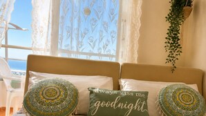 Uma cama bem arrumada com um travesseiro de padrão verde e branco, um travesseiro com a inscrição 'always kiss me goodnight' e uma toalha enrolada sobre a cama.