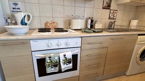 Uma cozinha compacta com forno embutido, máquina de lavar roupa e o símbolo de Wi-Fi.