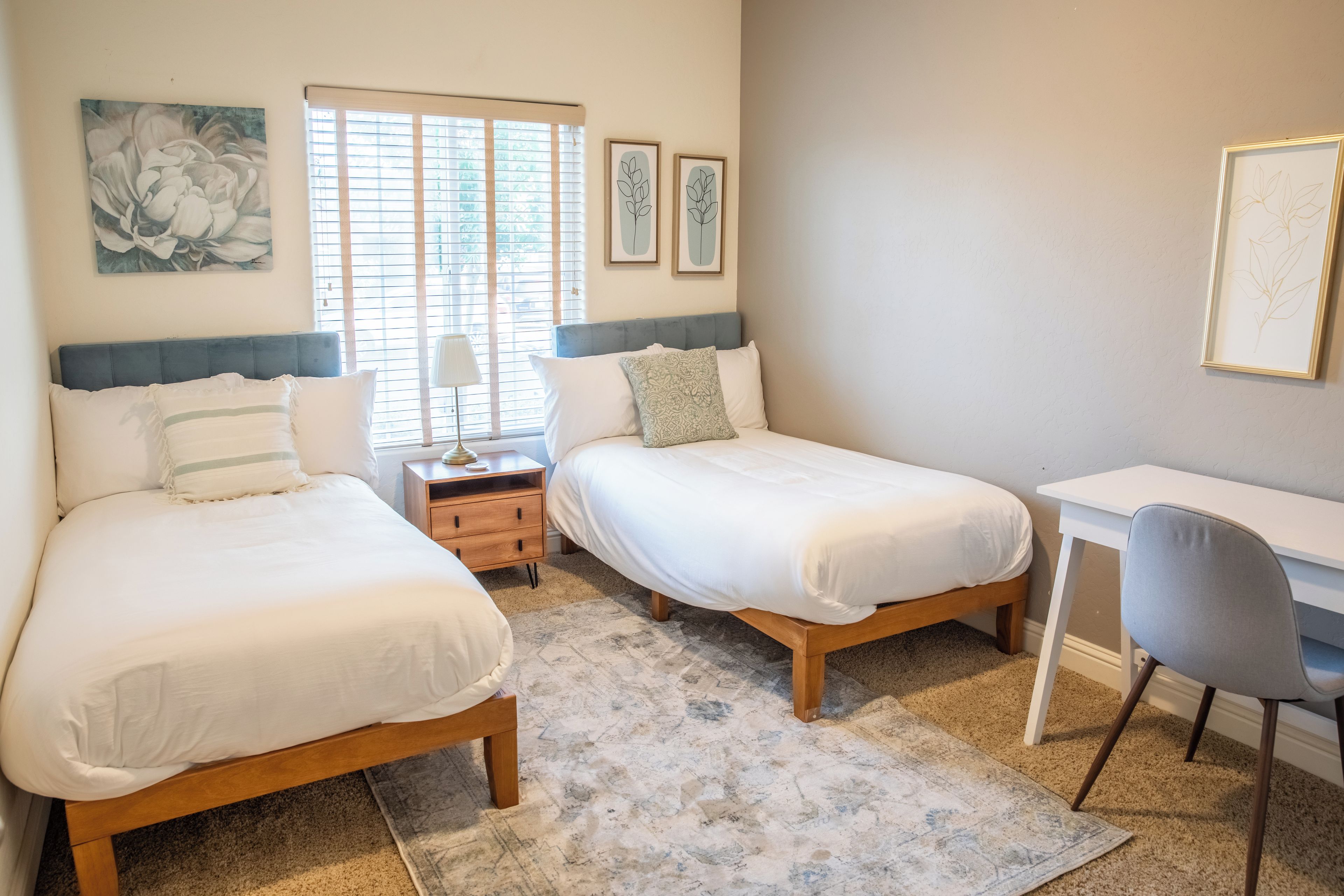 A bedroom with two beds, a desk, and a chair.