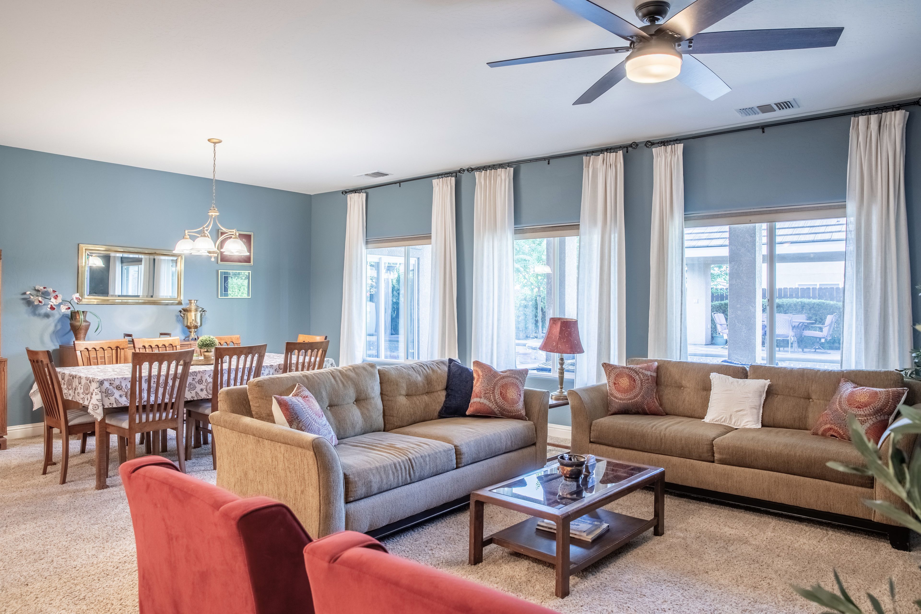 A living room with a sofa, armchairs, a coffee table, and a dining area with a table and chairs.