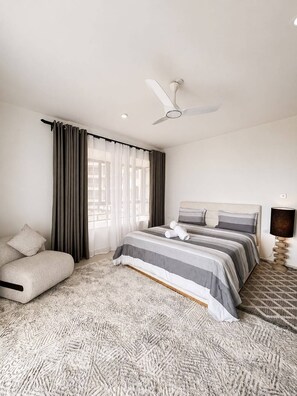 Ein Schlafzimmer mit einem Bett, einer Schlafcouch, einem Deckenventilator und einer Lampe.