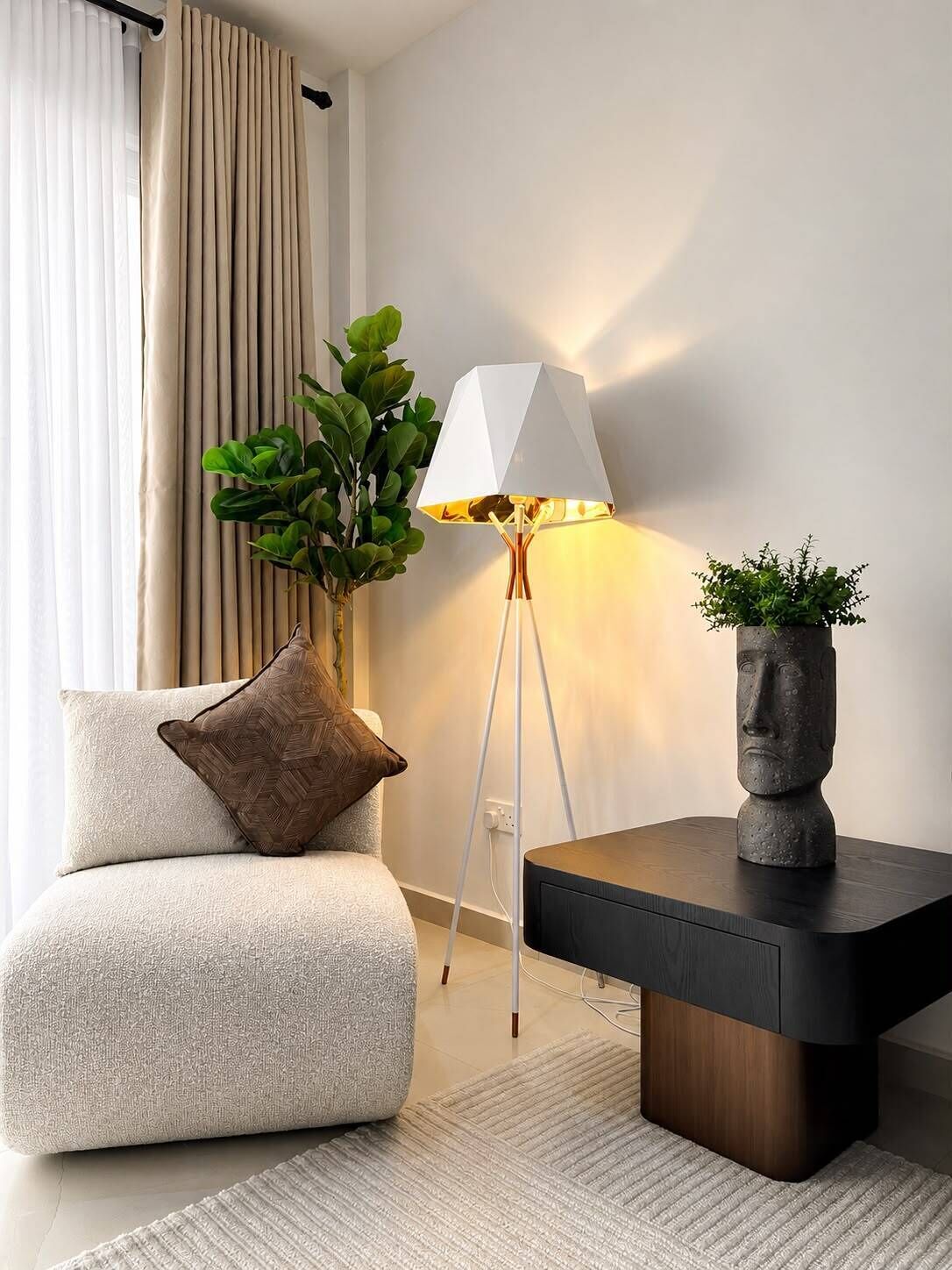 Ett modernt vardagsrum med en soffa, en golvlampa, en krukväxt och en dekorativ stenskulptur.