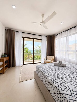 A hotel room with a bed, a chair, a desk, and a view of the outdoors. - Beach Apartment - right on the Beach! (with full Air Conditioning, Gym) (Mombasa)