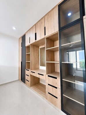 A modern, multi-shelved wardrobe with a minimalist design, featuring a combination of open and closed storage spaces, and a glass door on one side. - Beach Apartment - right on the Beach! (with full Air Conditioning, Gym) (Mombasa)