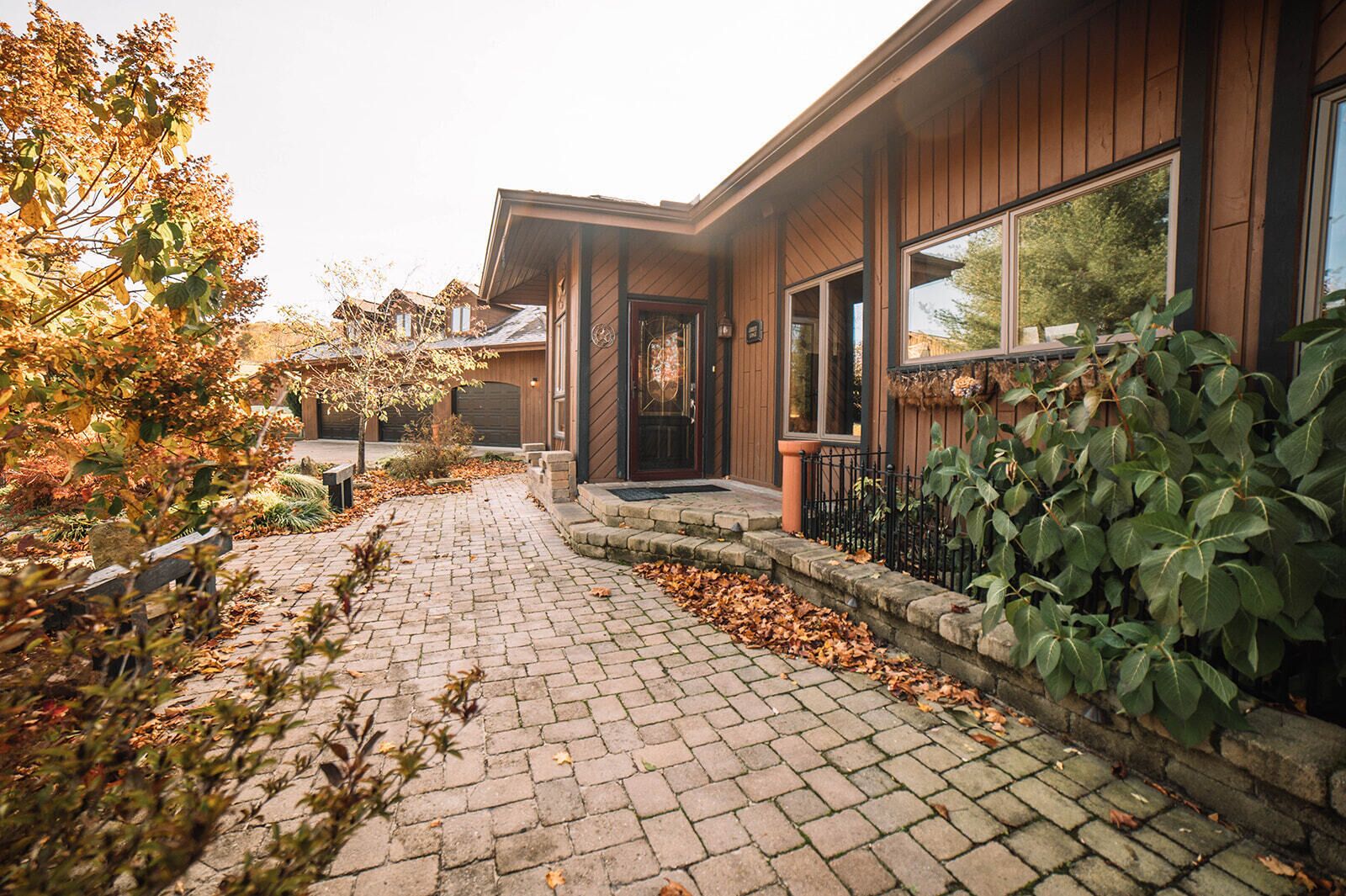 A residential building with a paved driveway, a front door, and a large window.