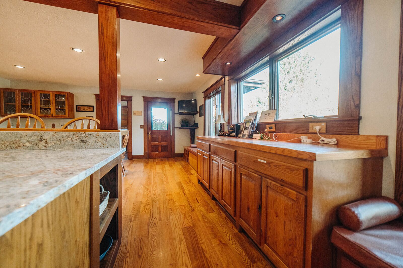 Une cuisine avec des meubles en bois, un plan de travail en marbre et une fenêtre qui laisse entrer la lumière naturelle.