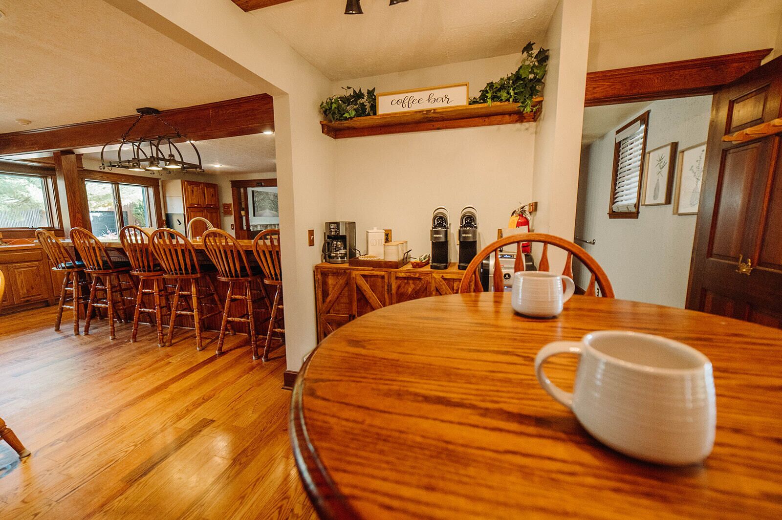Un espace repas comprenant une table en bois, des chaises et un coin café avec deux machines à café.