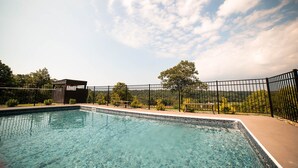 A clear swimming pool with a fenced area, surrounded by a wooden structure and a bench.