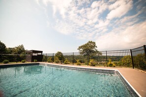 A clear swimming pool with a fenced area, surrounded by a wooden structure and a bench.