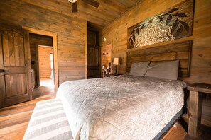 Une chambre à coucher en bois avec un grand lit, une table de chevet, une lampe et un élément décoratif mural.