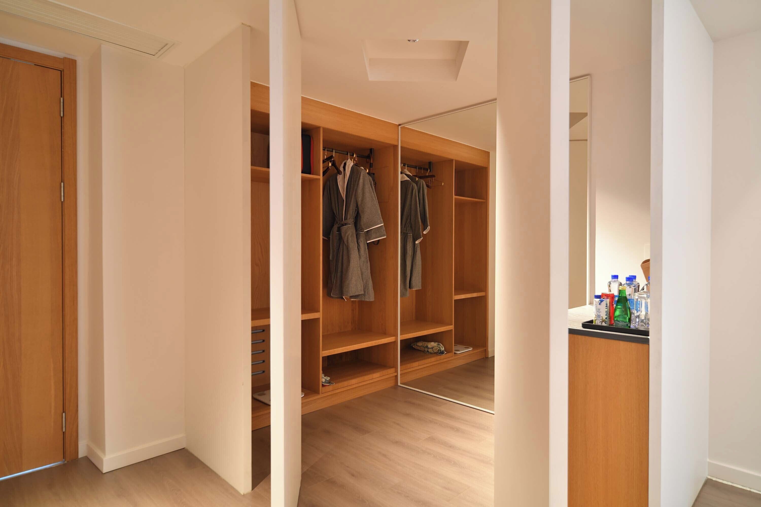 A walk-in closet with wooden shelving, a mirror, and a small countertop with bottles.