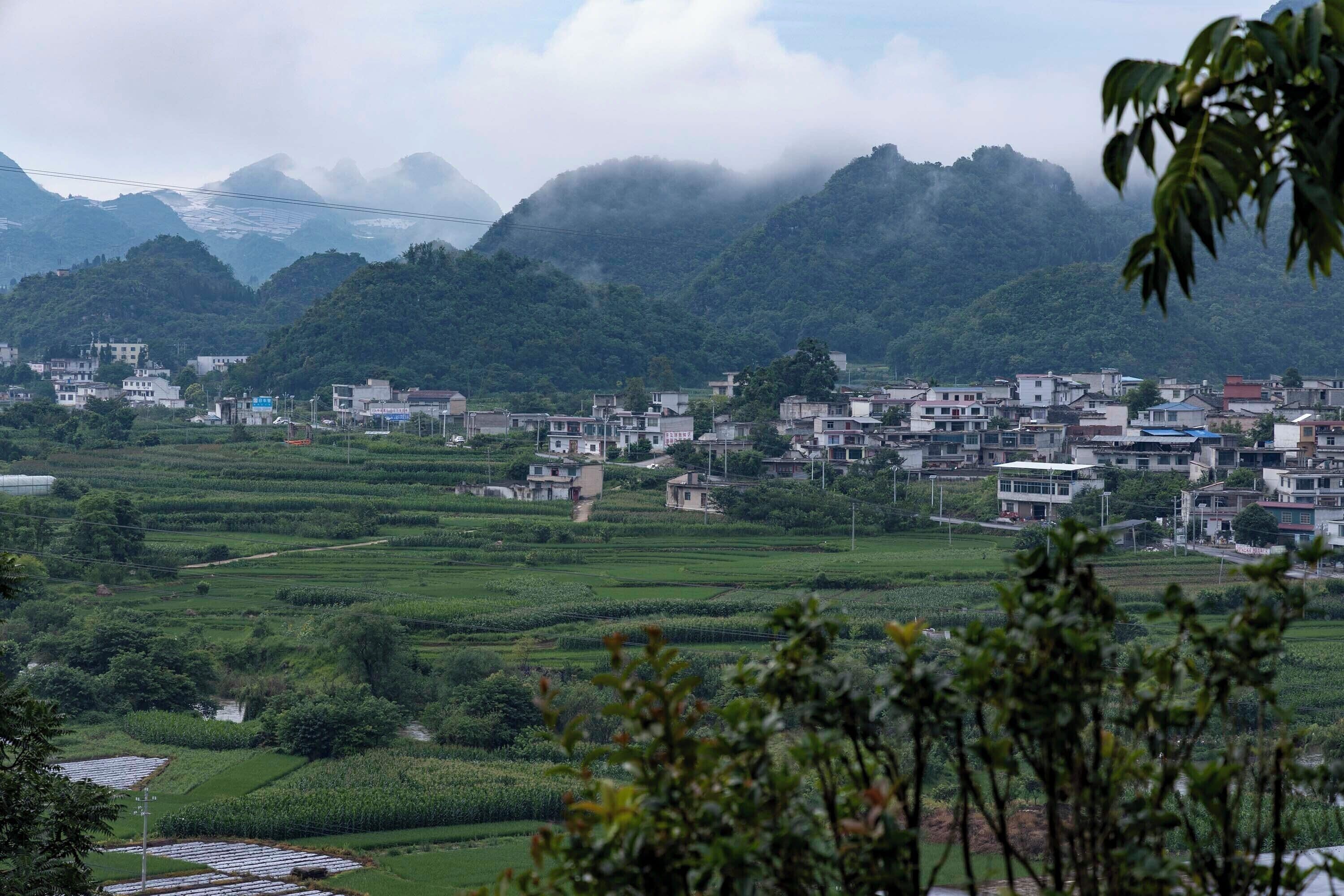 A town with terraced fields and buildings, surrounded by mountains.