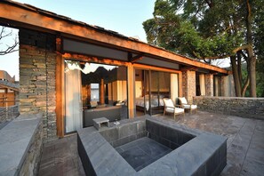 A modern house with a stone exterior, large glass doors, and a patio area with seating. - Zhiye Resort Hotel (Anshun)