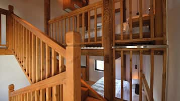 A wooden staircase leading to a loft bedroom with a bed and a window.